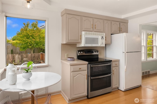 kitchen featuring visible vents, light countertops, baseboards, light wood finished floors, and white appliances