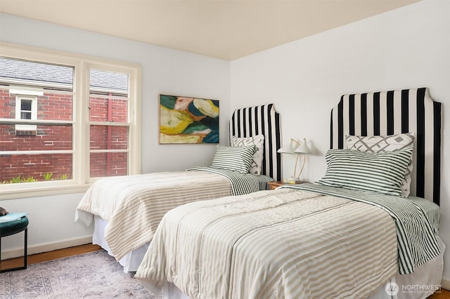 bedroom featuring baseboards, multiple windows, and wood finished floors