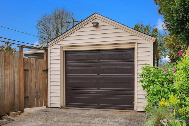 detached garage featuring fence and driveway