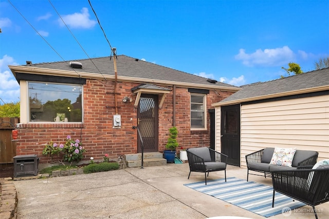 rear view of house featuring brick siding, a patio, outdoor lounge area, and roof with shingles