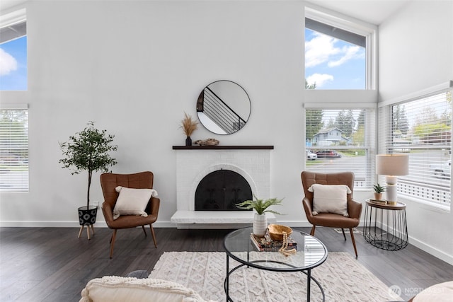 living room featuring baseboards, a high ceiling, wood finished floors, and a fireplace