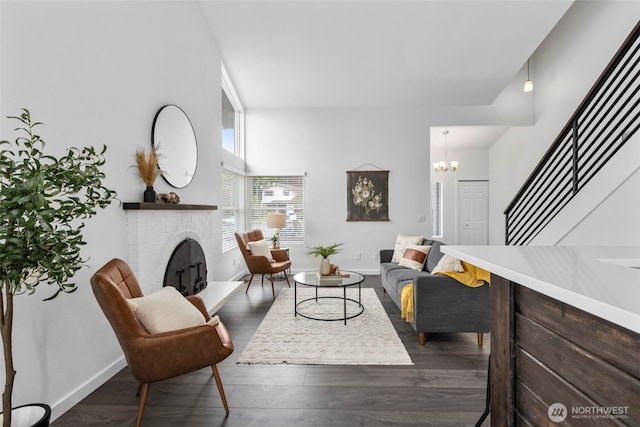 living area with stairway, a chandelier, a fireplace, dark wood finished floors, and baseboards