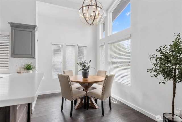 dining space featuring baseboards, a notable chandelier, a towering ceiling, and dark wood-style floors