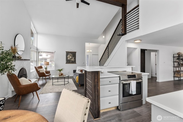 kitchen featuring white cabinets, stainless steel range with electric cooktop, open floor plan, and a high ceiling