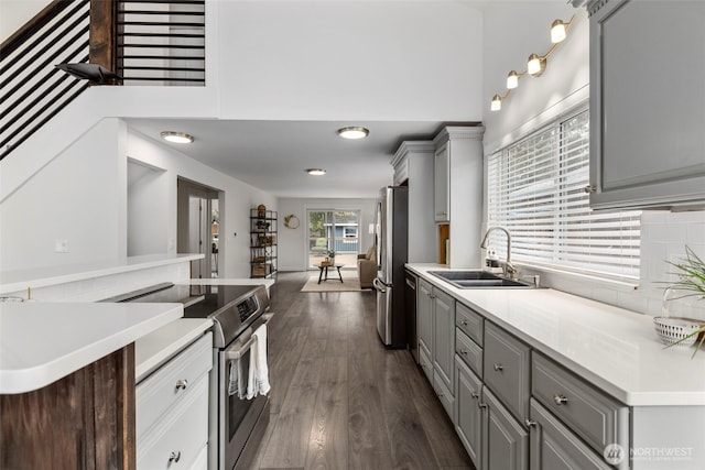 kitchen with gray cabinets, stainless steel appliances, light countertops, and a sink