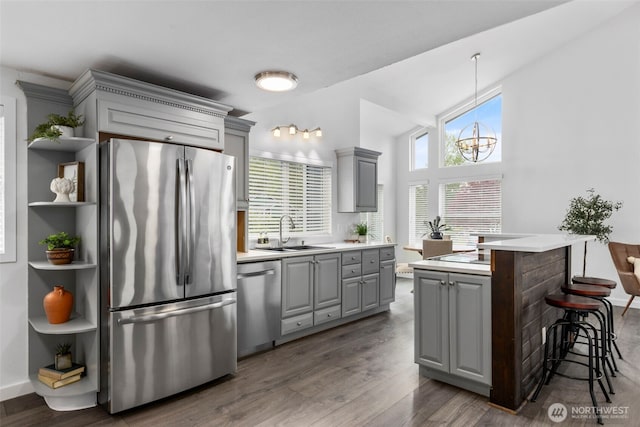 kitchen with stainless steel appliances, light countertops, gray cabinetry, and a sink