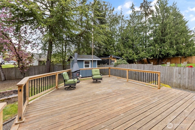 wooden terrace with a fenced backyard, an outdoor structure, and a shed