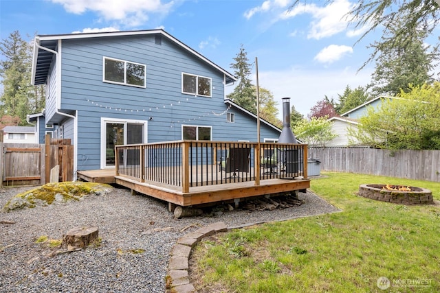 rear view of property featuring a fenced backyard, a wooden deck, a yard, and an outdoor fire pit