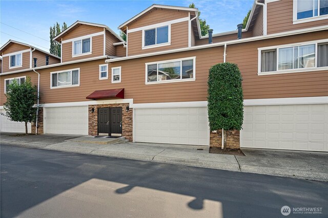 townhome / multi-family property featuring an attached garage and stone siding