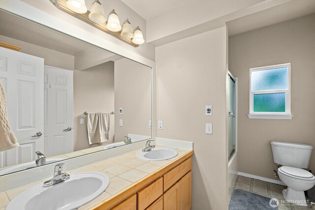 full bathroom featuring a sink, tile patterned flooring, toilet, and double vanity