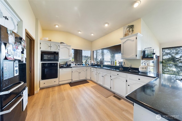 12724 Marine Dr, Anacortes, WA 98221 - kitchen with plenty of natural light, vaulted ceiling, visible vents, light wood-style floors, and black appliances