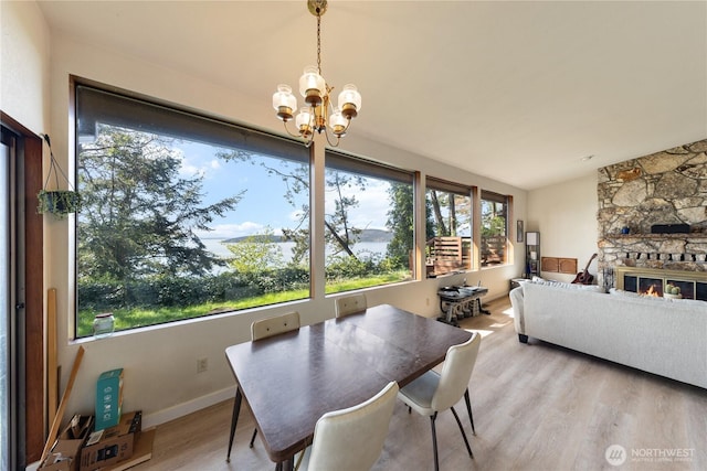 12724 Marine Dr, Anacortes, WA 98221 - dining room featuring a chandelier, light wood-type flooring, baseboards, and a stone fireplace