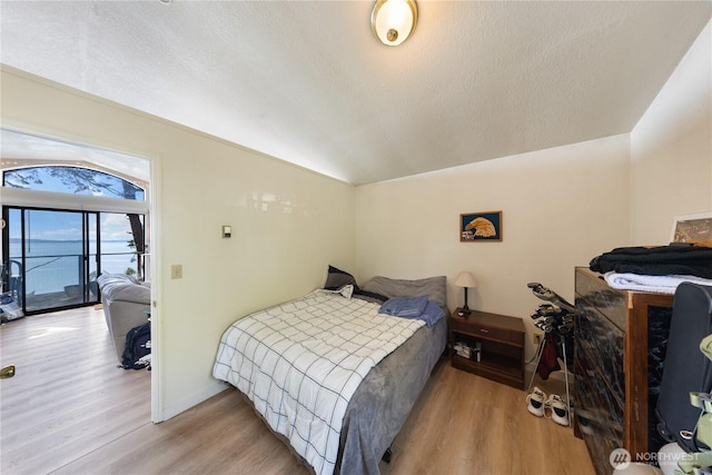 12724 Marine Dr, Anacortes, WA 98221 - bedroom featuring vaulted ceiling, wood finished floors, access to exterior, baseboards, and a textured ceiling