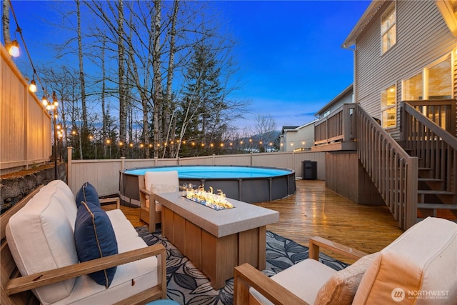 wooden deck featuring a fenced in pool, an outdoor living space with a fire pit, a fenced backyard, and stairway