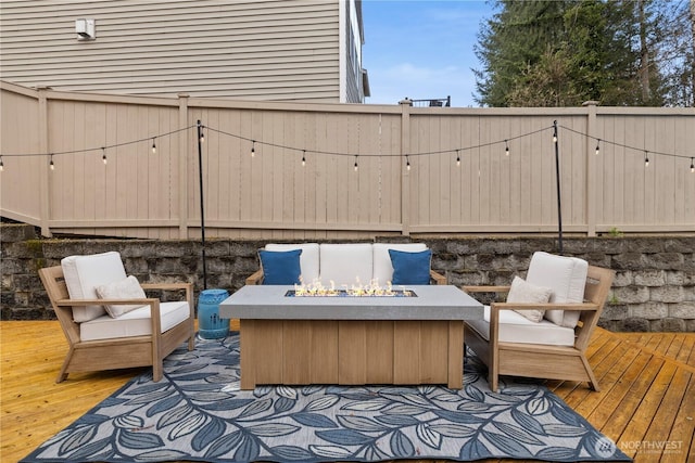 wooden terrace with a fire pit and a fenced backyard
