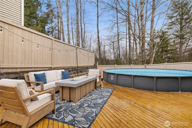 wooden terrace with fence, a fenced in pool, and an outdoor living space with a fire pit