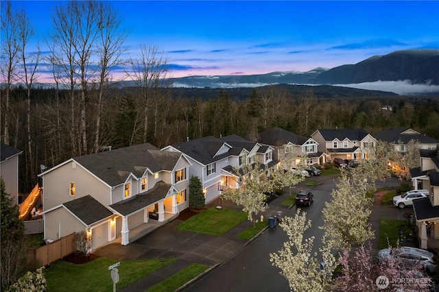 aerial view at dusk with a residential view, a wooded view, and a mountain view