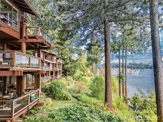view of yard featuring a deck with water view and view of wooded area