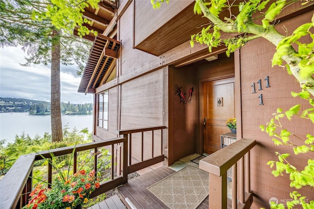 view of exterior entry with a deck with water view