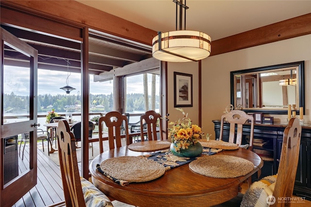 dining space with beamed ceiling, healthy amount of natural light, and wood finished floors