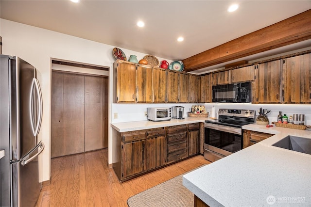 kitchen featuring stainless steel appliances, light countertops, recessed lighting, light wood-type flooring, and a sink
