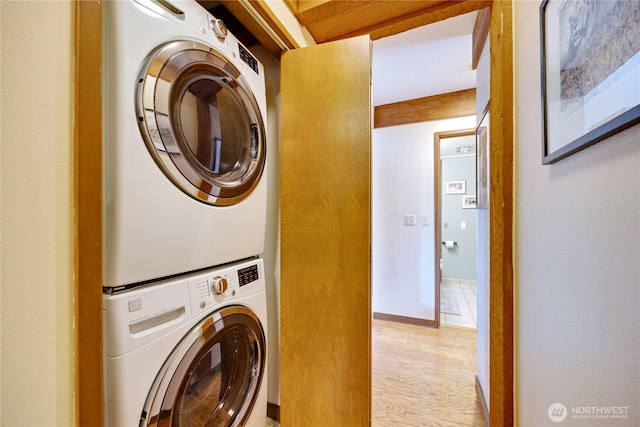 laundry area with stacked washer / drying machine and light wood finished floors