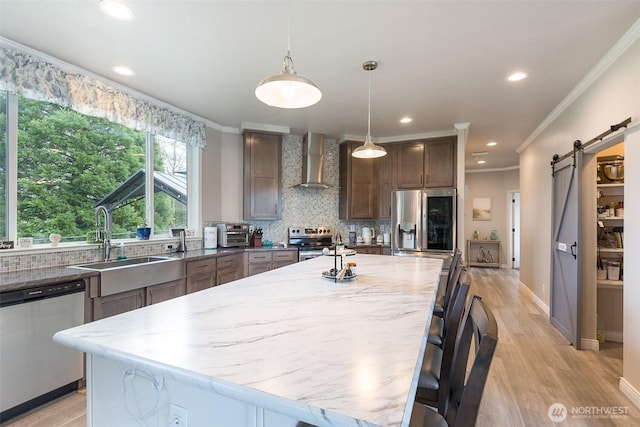 kitchen featuring appliances with stainless steel finishes, a sink, tasteful backsplash, and wall chimney exhaust hood