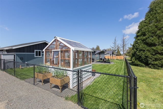 back of house with fence, board and batten siding, a greenhouse, an outbuilding, and a lawn