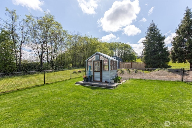 view of greenhouse featuring a fenced backyard and a lawn