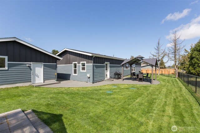 rear view of property with a lawn, fence, board and batten siding, and a patio