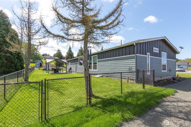 view of home's exterior with board and batten siding, a yard, a gate, fence, and crawl space