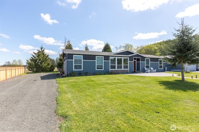 view of front of property featuring fence, board and batten siding, a front yard, and a patio area
