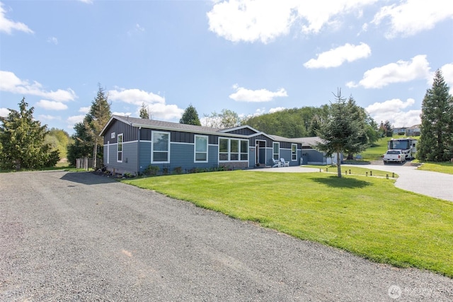 view of front of home with a front lawn, gravel driveway, and board and batten siding