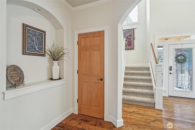 foyer featuring crown molding, stairs, wood finished floors, and plenty of natural light