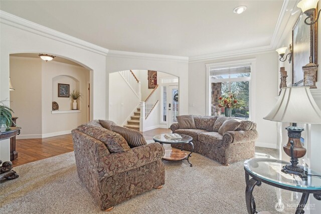 living area featuring stairway, wood finished floors, arched walkways, crown molding, and baseboards