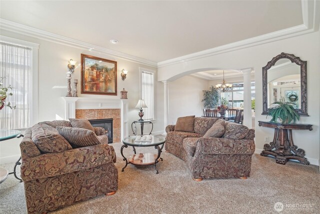 carpeted living room with decorative columns, crown molding, and plenty of natural light