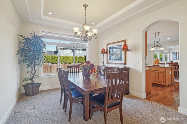 dining room with an inviting chandelier, carpet floors, baseboards, and arched walkways