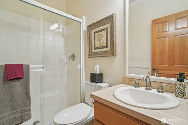 bathroom featuring a stall shower, toilet, and vanity