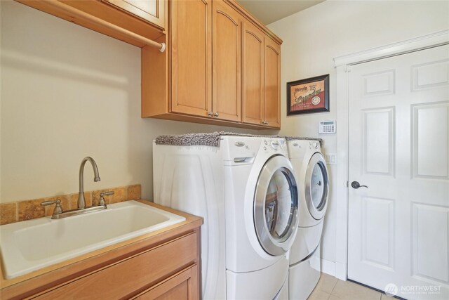 laundry area with light tile patterned floors, a sink, washing machine and clothes dryer, and cabinet space