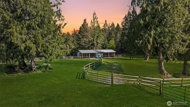 surrounding community with fence, an outbuilding, an exterior structure, a rural view, and a lawn