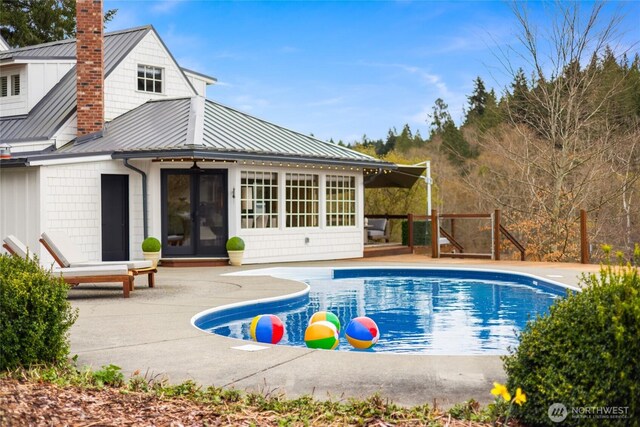 rear view of house with a standing seam roof, a patio area, metal roof, a chimney, and french doors