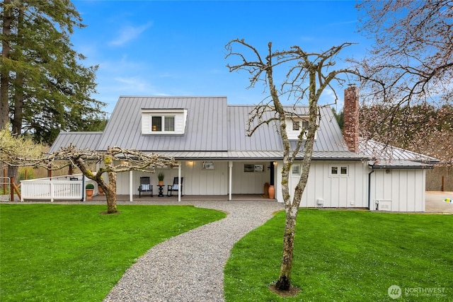 rear view of house with metal roof, a lawn, and board and batten siding