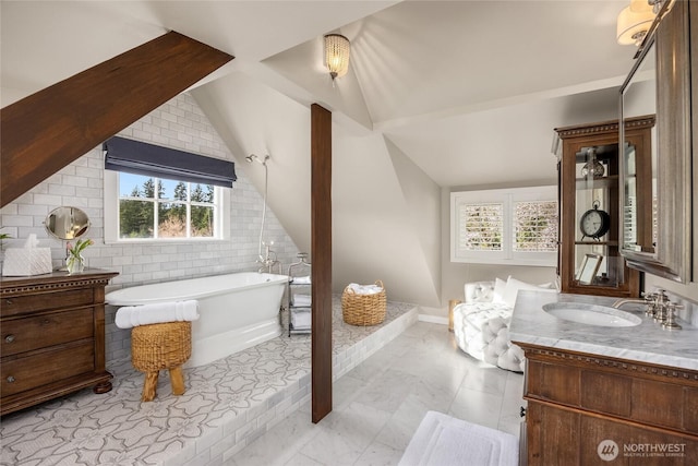 bathroom with a freestanding tub, lofted ceiling, and vanity