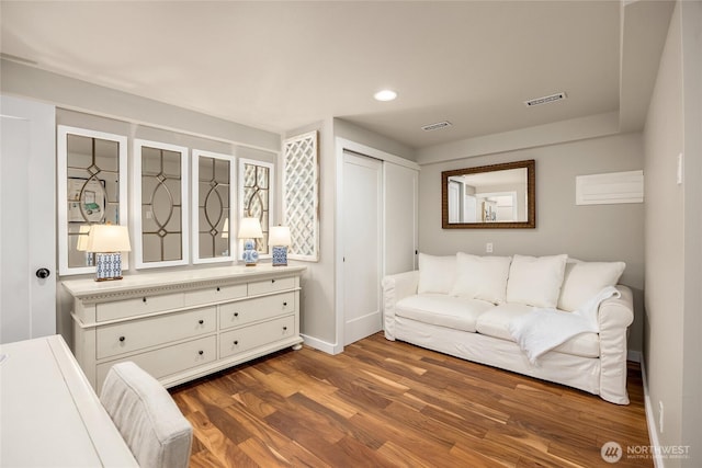 living room featuring baseboards, visible vents, wood finished floors, and recessed lighting