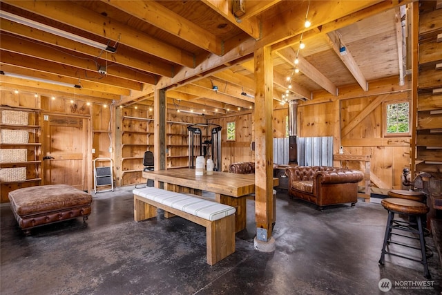 living area with wooden walls, concrete floors, beamed ceiling, and a wealth of natural light