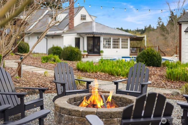 back of house with an outdoor fire pit and metal roof