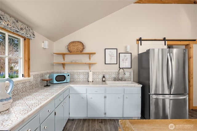 kitchen with lofted ceiling, a sink, freestanding refrigerator, dark wood finished floors, and white microwave