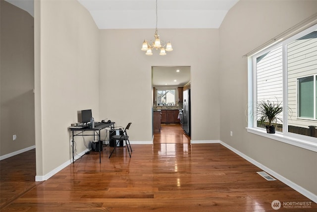 interior space featuring dark wood finished floors, visible vents, an inviting chandelier, and lofted ceiling