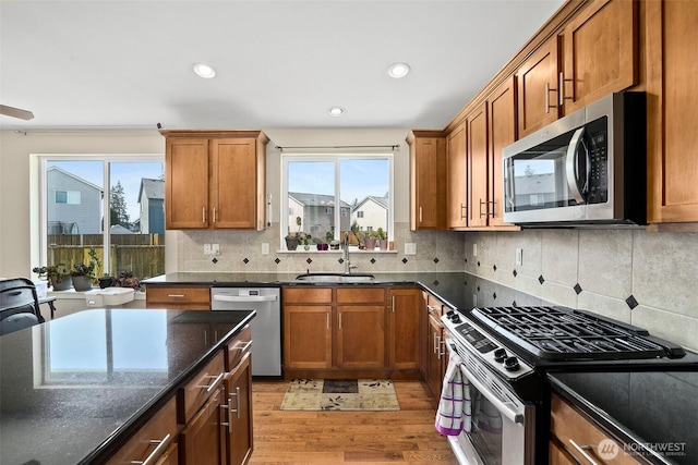 kitchen featuring brown cabinets, a sink, a healthy amount of sunlight, stainless steel appliances, and light wood finished floors