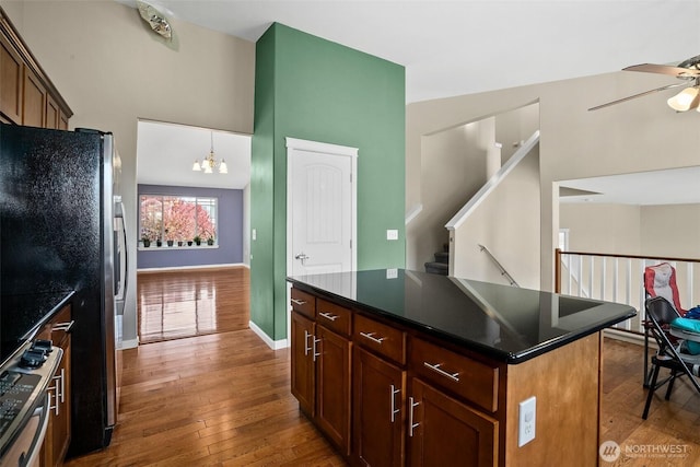 kitchen with dark countertops, freestanding refrigerator, hardwood / wood-style flooring, and ceiling fan with notable chandelier